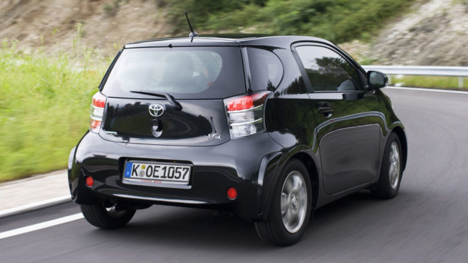 Kurvenfahrt eines schwarzen Toyota iQ auf einer Landstraße.