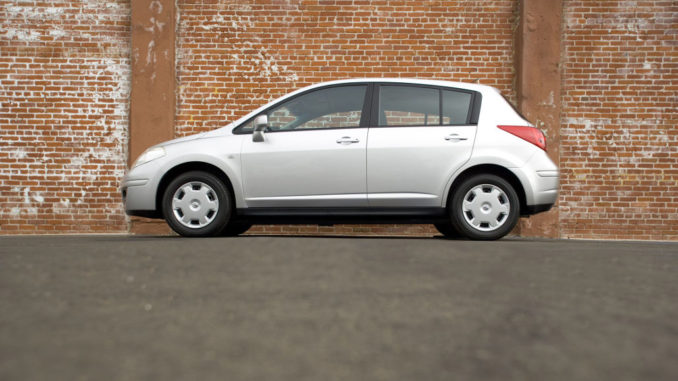 Ein silberner Nissan Versa steht in den USA vor einer Ziegelmauer, in Europa heißt das Modell Tiida