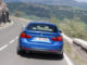 Ein blaues BMW 428i Gran Coupé fährt auf einer Bergstraße auf eine Kurve zu.