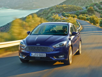 Ein blauer Ford Focus fährt 2014 auf einer Landstraße bei Abendlicht.