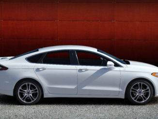 Ein weißer Ford Fusion (Mondeo) Titanium des Modelljahres 2014 steht vor einer roten Wand.