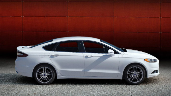 Ein weißer Ford Fusion (Mondeo) Titanium des Modelljahres 2014 steht vor einer roten Wand.