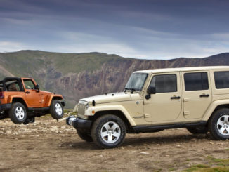 Zwei Jeep Wrangler, ein roter Zweitürer und ein beiger Viertürer, stehen im Gelände vor einer Bergkulisse.