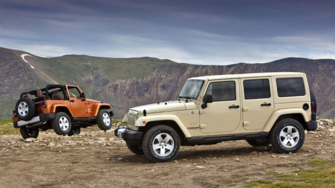 Zwei Jeep Wrangler, ein roter Zweitürer und ein beiger Viertürer, stehen im Gelände vor einer Bergkulisse.