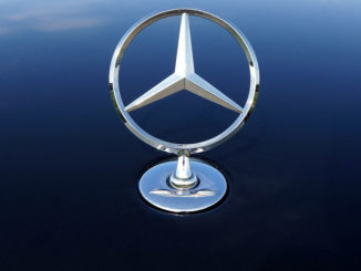 Ein Mercedes-Stern in Großaufnahme auf einer blauen Motorhaube.
