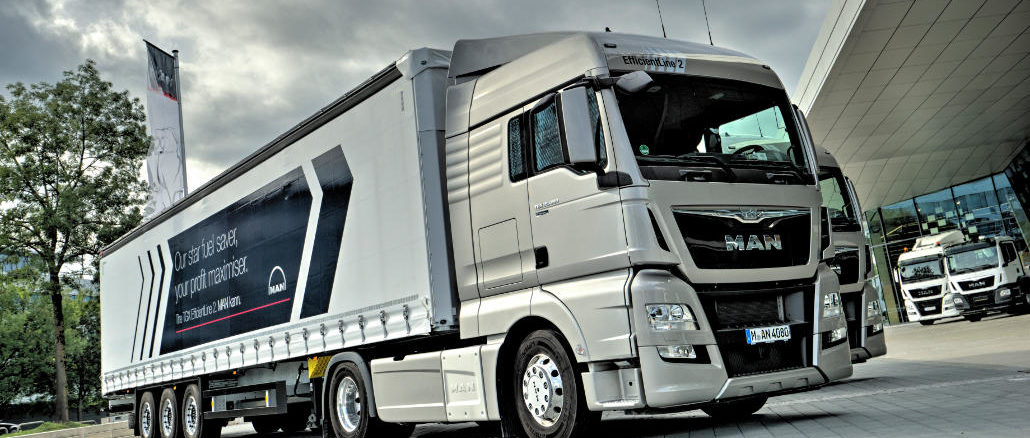 Ein silberner Lkw MAN TGX steht 2016 bei bewölktem Himmel vor einer Halle.