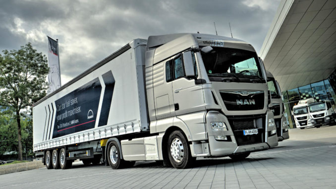 Ein silberner Lkw MAN TGX steht 2016 bei bewölktem Himmel vor einer Halle.