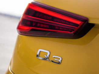 Logo der Q3-Baureihe am Heck eines gelben Audi.
