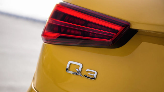 Logo der Q3-Baureihe am Heck eines gelben Audi.