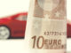 Zehn-Euro-Schein im Vordergrund und Modell eines Sportwagens im Hintergrund