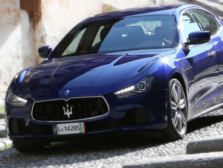 Ein blauer Maserati Ghibli fährt eine steile Straße hinab.