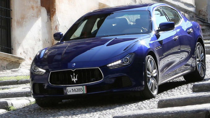 Ein blauer Maserati Ghibli fährt eine steile Straße hinab.