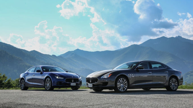 Ein blauer Maserati Ghibli und ein grauer Maserati Quattroporte, Modelljahr 2015, stehen vor einer Bergkulisse.