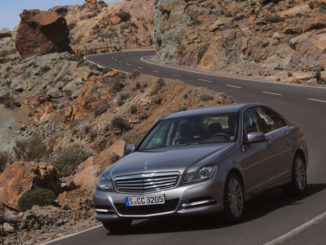 Ein silberner Mercedes-Benz C-Klasse (W204) fährt durch eine Vulkanlandschaft. Mercedes-Benz C-Klasse, C 350 ELEGANCE Limousine (W204; Jahr 2011), palladiumsilber metallic, Leder beige.