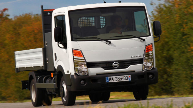 Ein weißer Nissan Cabstar fährt auf einer Straße durch Herbstlandschaft.