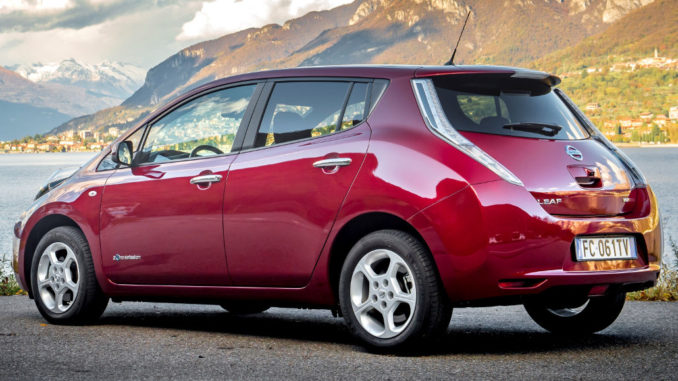 Ein roter Nissan Leaf steht vor einem See in Italien.