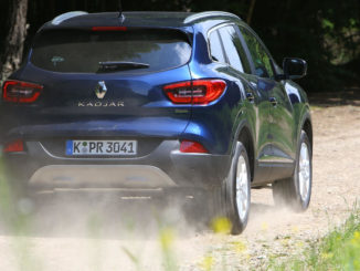 Ein blauer Renault Kadjar fährt auf einem Waldweg.