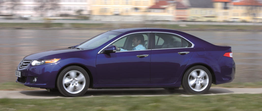 Ein blauer Honda Accord fhrt an einem Flussufer entlang.