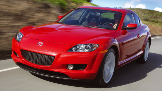 Ein roter Mazda RX-8 der ersten Generation fährtauf einer Landstraße