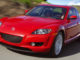 Ein roter Mazda RX-8 der ersten Generation fährtauf einer Landstraße