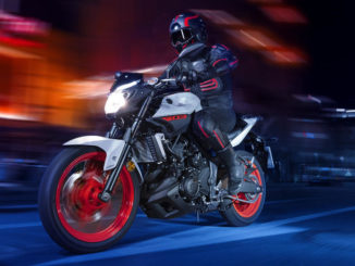 Eine grau-schwarze Yamaha MT-03 mit roten Felgen fährt durch die Nacht.