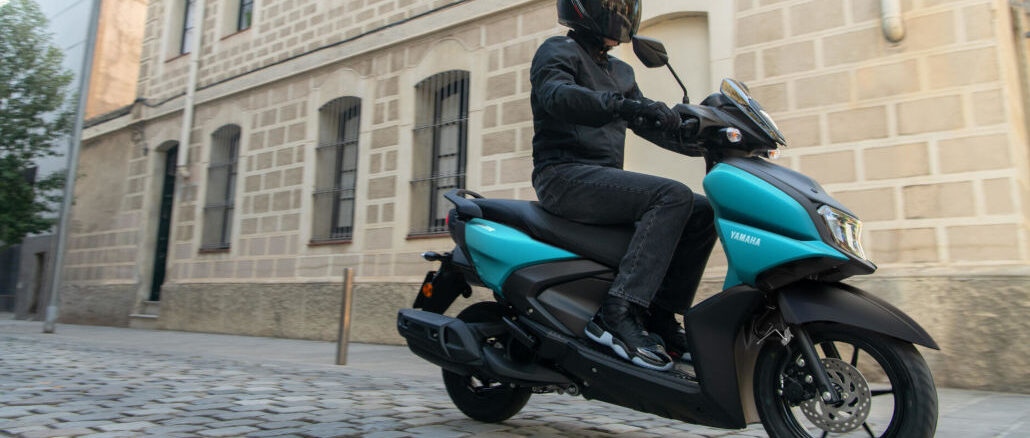 Eine blaue Yamaha RayZR fährt 2025 über Kopfsteinpflaster.
