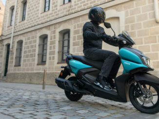 Eine blaue Yamaha RayZR fährt 2025 über Kopfsteinpflaster.