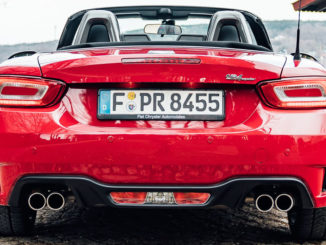 Ein roter Abarth 124 Spider steht 2018 an einem Seeufer.