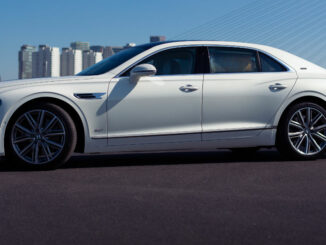 Ein weißer Bentley Flying Spur steht 2022 vor der Skyline von Rotterdam.