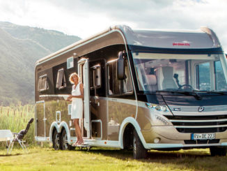 Ein beiges Dethleffs-Wohnmobil vom Typ Globetrotter XLI (MJ 2019) steht neben einem Campingtisch in einem Naturpark.