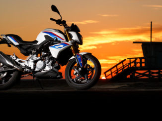 Eine BMW G 310 R steht an einem Strand im Sonnenuntergang.