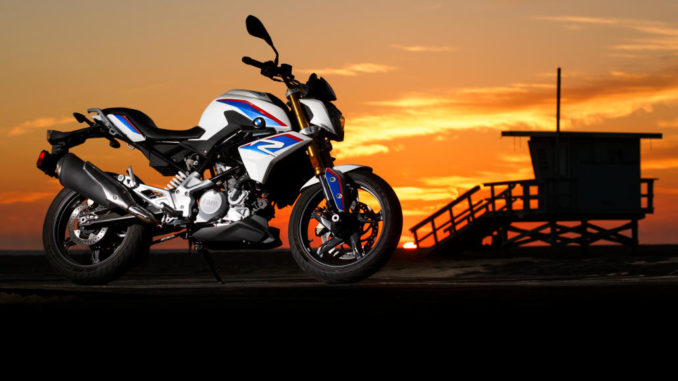 Eine BMW G 310 R steht an einem Strand im Sonnenuntergang.