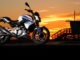 Eine BMW G 310 R steht an einem Strand im Sonnenuntergang.