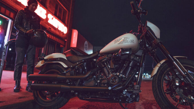 Eine weiße Harley-Davidson Low Rider S steht 2023 nachts vor einer Bar.