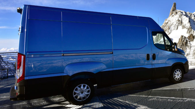 Ein blauer Iveco Daily steht vor einem Berggipfel.