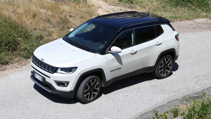 Ein weißer Jeep Compass auf einem sommerlichen Feldweg.