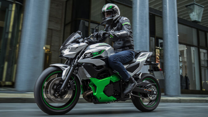 Eine Kawasaki Z7 Hybrid fährt 2024 an einem Bürogebäude vorbei.