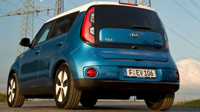 Ein blauer Kia Soul EV (PS) steht vor einem Strommast.