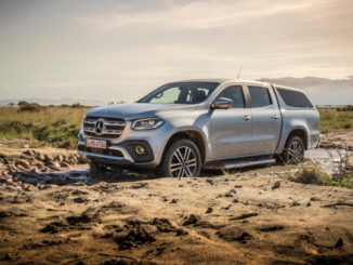 Eine silberne Mercedes X-Klasse mit Hardtop fährt im Gelände durch eine Pfütze.