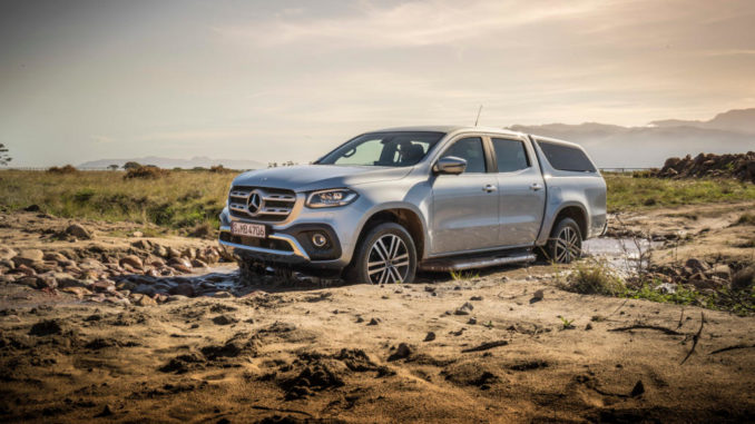 Eine silberne Mercedes X-Klasse mit Hardtop fährt im Gelände durch eine Pfütze.