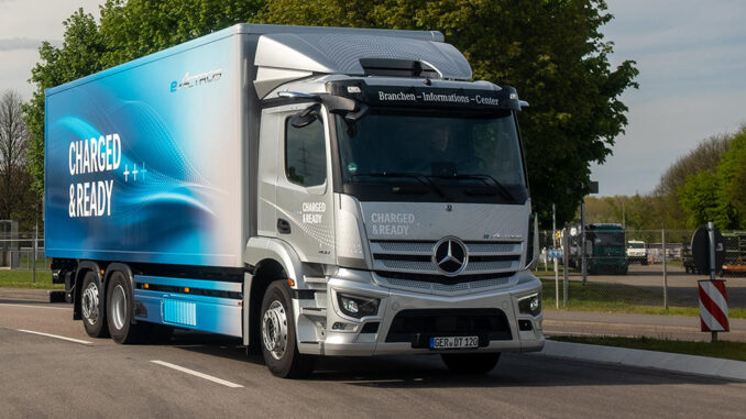 Ein silberner Startschuss Mercedes E-Actros fährt im Rahmen einer Roadshow auf einer Landstraße. Motto: quer durch Europa mit vollelektrischen Lkw