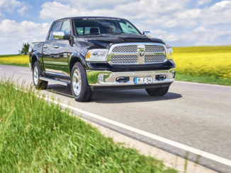 Ein schwarzer Pick-up RAM 1500 mit Autogasanlage fährt auf einer Landstraße vor einem Rapsfeld.