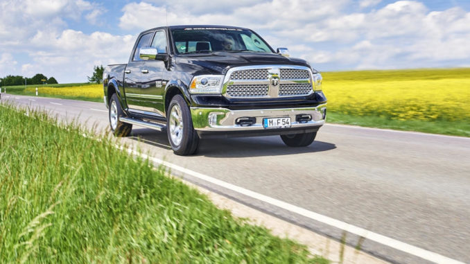 Ein schwarzer Pick-up RAM 1500 mit Autogasanlage fährt auf einer Landstraße vor einem Rapsfeld.