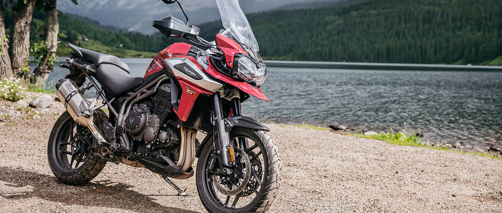 Eine rote Triumph Tiger 1200 steht 2018 an einem Seeufer.