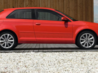 Ein roter Audi A3 steht 2010 vor einer Holzfassade.