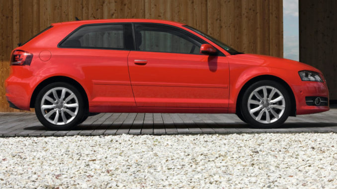 Ein roter Audi A3 steht 2010 vor einer Holzfassade.