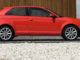 Ein roter Audi A3 steht 2010 vor einer Holzfassade.