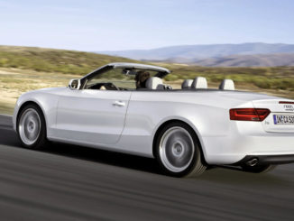 Ein weißes Audi A5 Cabrio fährt durch eine Wüstenlandschaft.