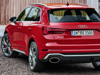 Ein roter Audi RS Q3 steht 2019 vor einem Holzhaus.