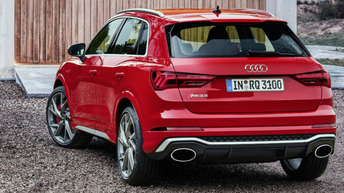 Ein roter Audi RS Q3 steht 2019 vor einem Holzhaus.